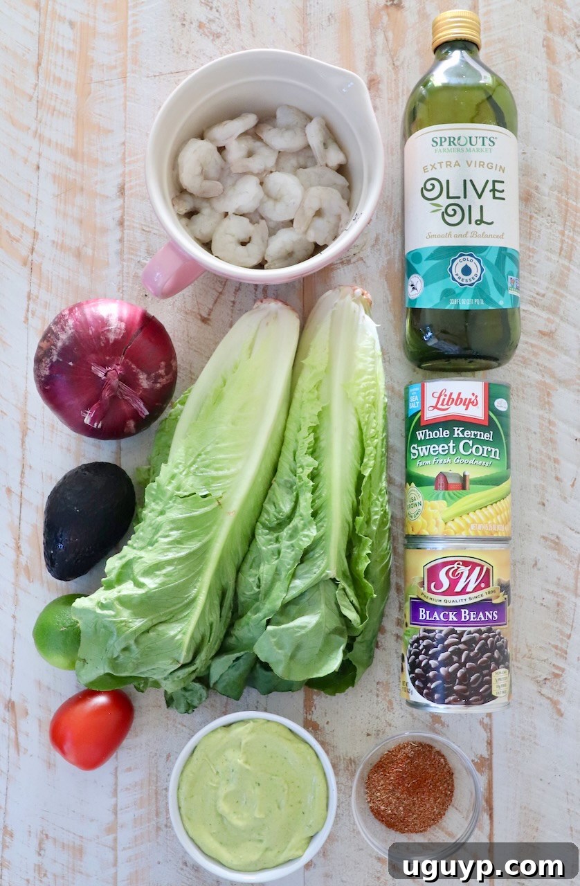 A collection of fresh ingredients for Mexican shrimp salad laid out on a white wooden board, including shrimp, avocado, corn, beans, and fresh produce.