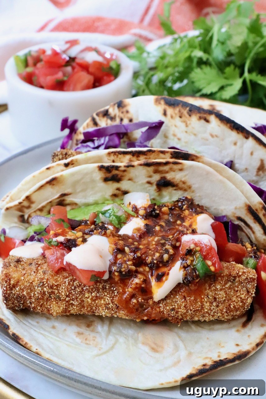 fish taco with crispy breading, topped with vibrant salsa, creamy sauce, and shredded red cabbage, set against fresh cilantro and a small salsa dish.