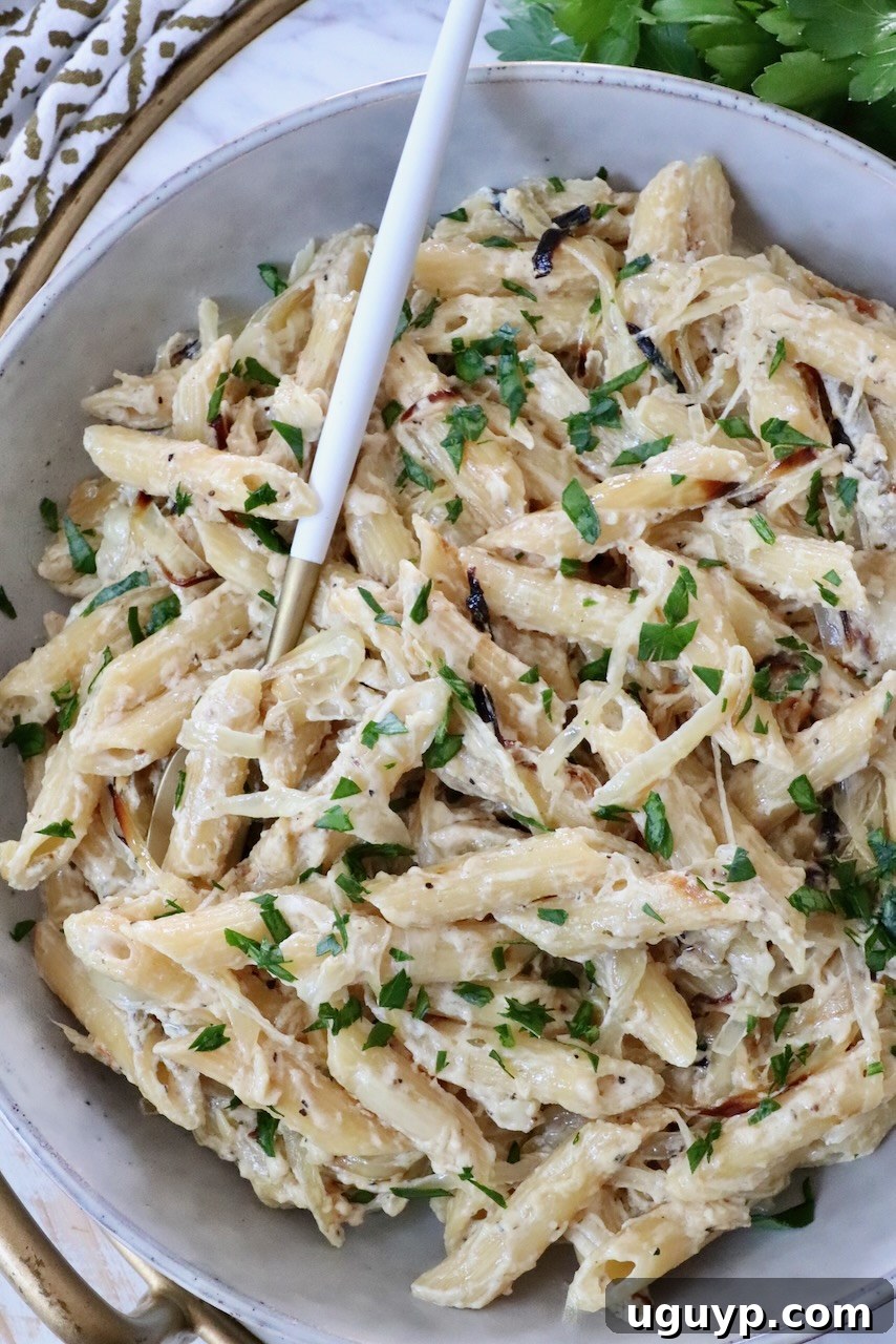 cooked penne pasta in a creamy sauce in a bowl with a fork