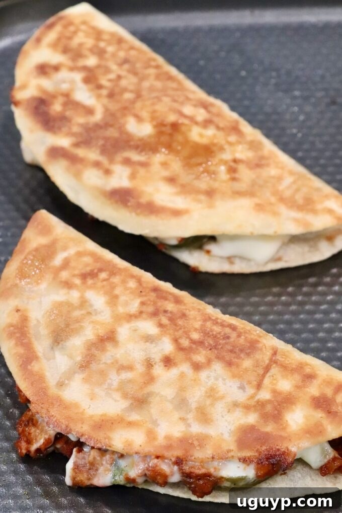 Two golden-brown crispy tacos sizzling in a hot pan, their exteriors perfectly toasted, revealing hints of melted cheese and chorizo within.