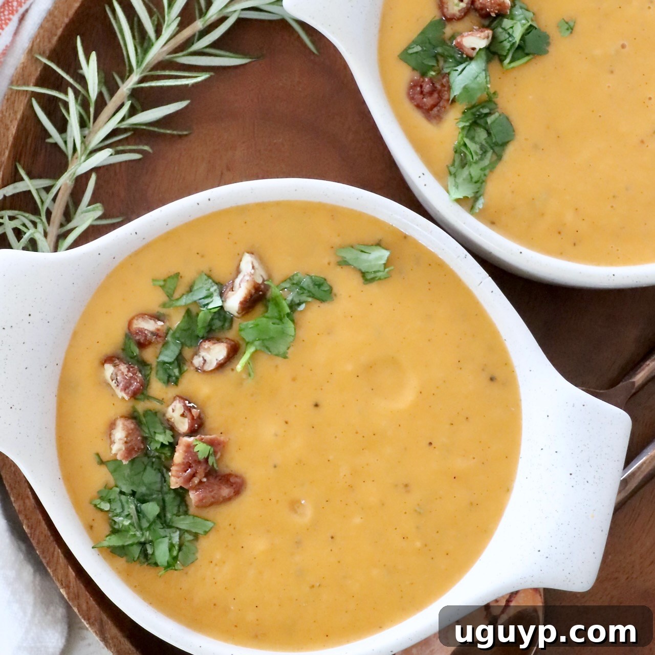 Creamy Sweet Potato Soup in bowls, garnished with fresh parsley and candied pecans for a touch of sweetness and crunch.