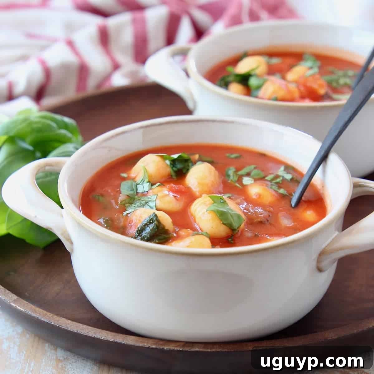 Delicious Tomato Basil Gnocchi Soup served in white bowls on a rustic wooden tray.