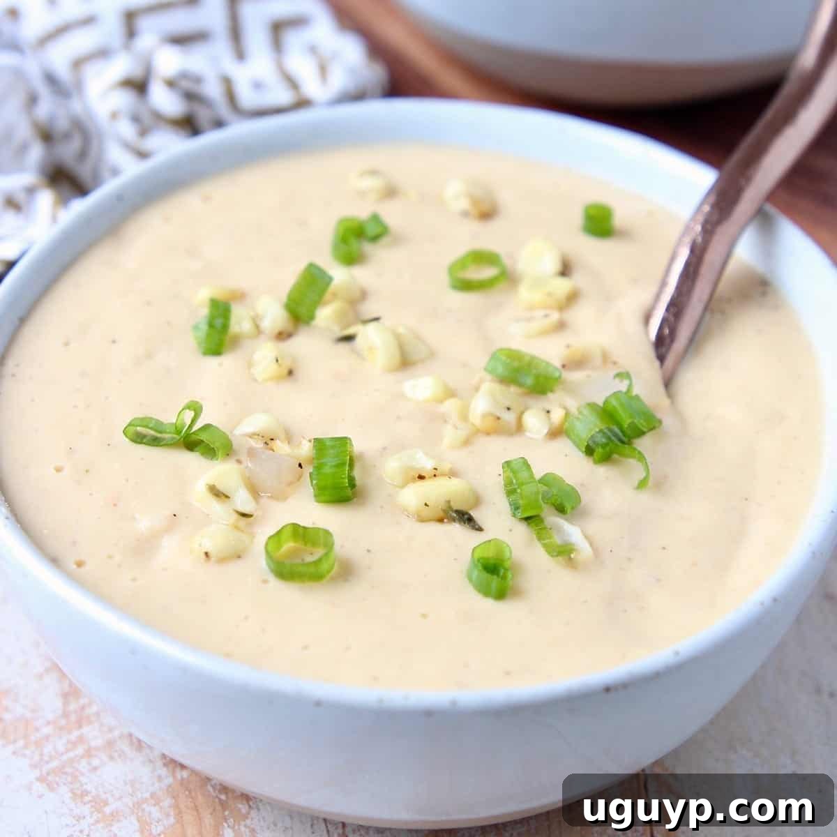 Creamy Corn Soup in a bowl, topped with fresh corn kernels and diced green onions for vibrant color and flavor.