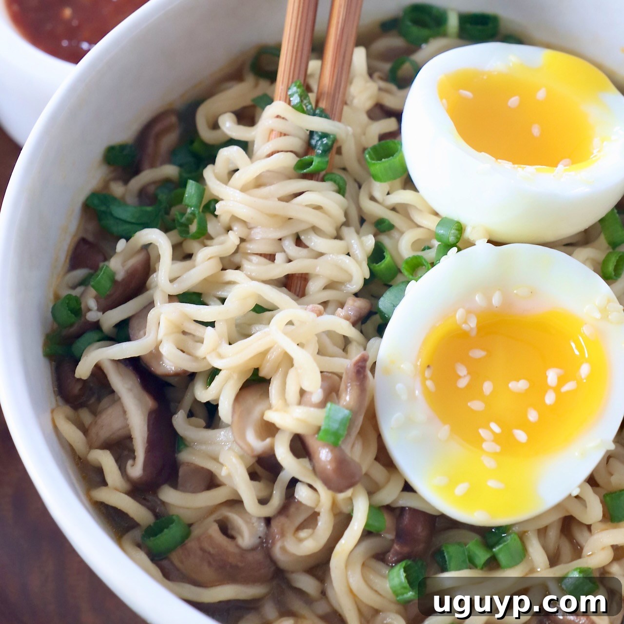 Perfectly cooked ramen noodles in a bowl with chopsticks and a soft-boiled egg, ready to be enjoyed.