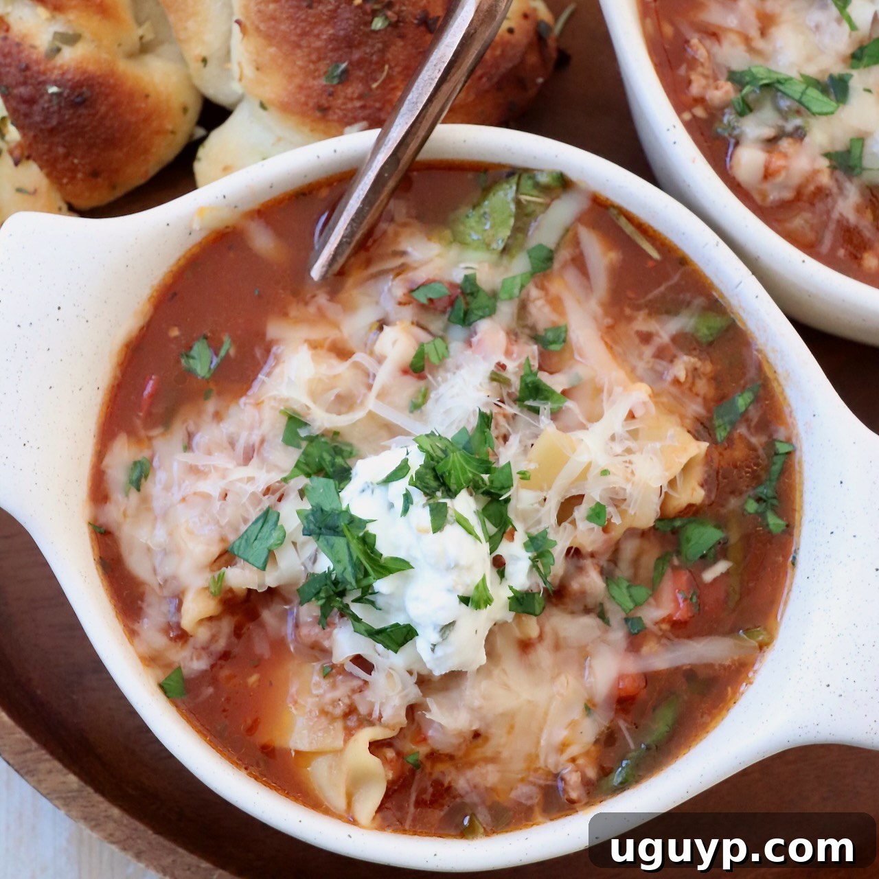 Hearty Lasagna Soup, generously topped with melted cheese, served in a bowl with a spoon.