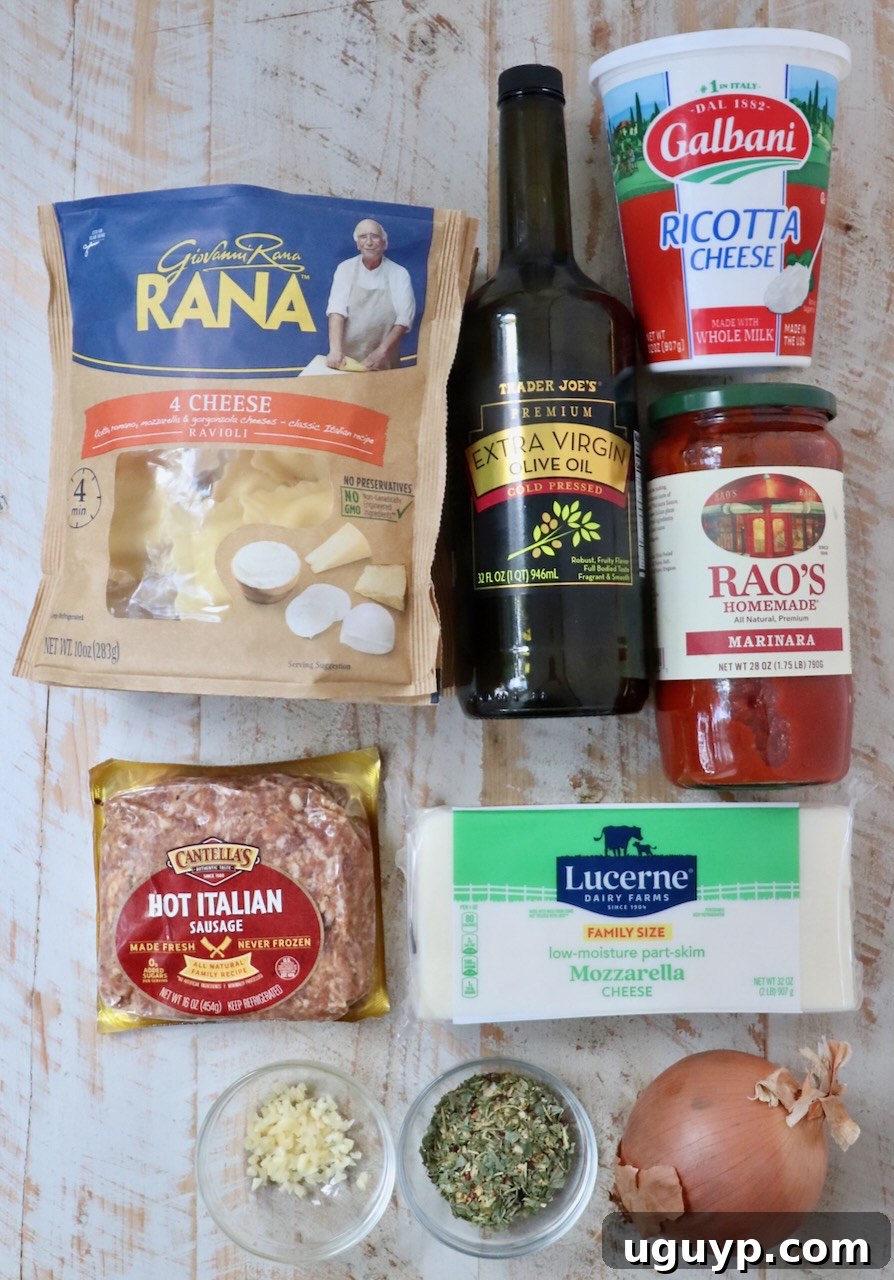 A rustic wooden table displays a bounty of fresh Italian ingredients. Key components include packages of cheese ravioli, a jar of rich marinara sauce, fresh ricotta and mozzarella cheeses, plump Italian sausages, golden olive oil, garlic, a red onion, and fragrant sprigs of fresh basil and oregano.