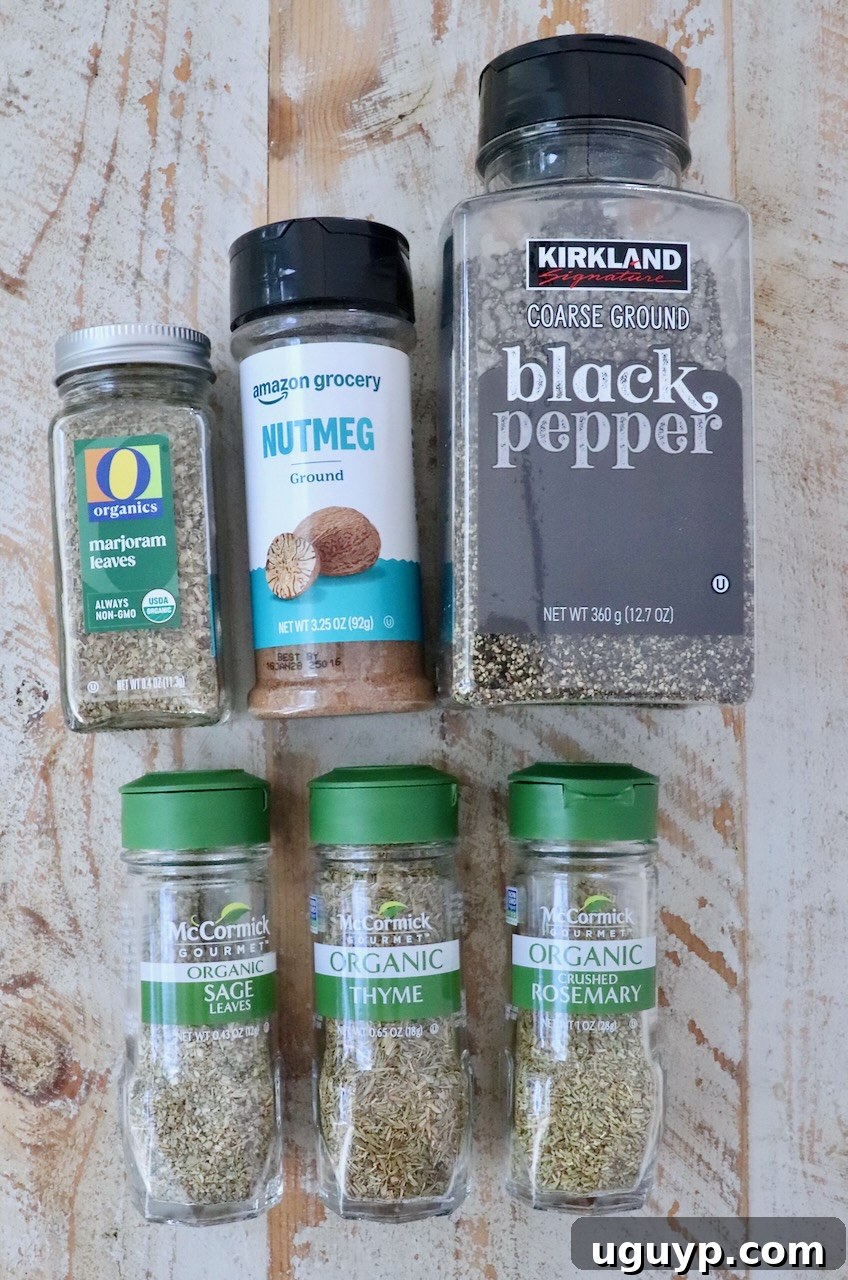 A collection of six spice bottles on a wooden surface, including black pepper, nutmeg, marjoram, sage, thyme, and rosemary, all in clear containers.