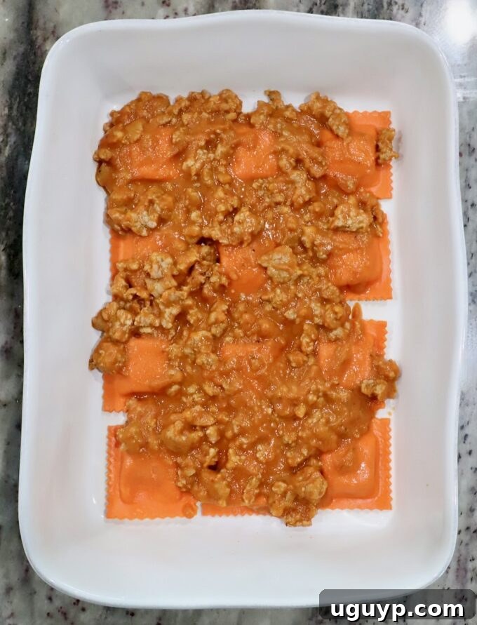 pumpkin ravioli in a baking dish, topped with butternut squash meat sauce