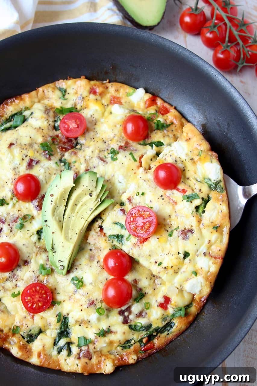 A slice of frittata being carefully lifted out of the skillet with a spatula, showcasing its texture and ingredients.