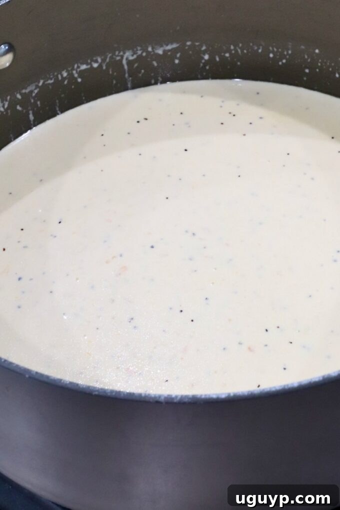 A pot filled with creamy white sauce speckled with small black and red flakes. 