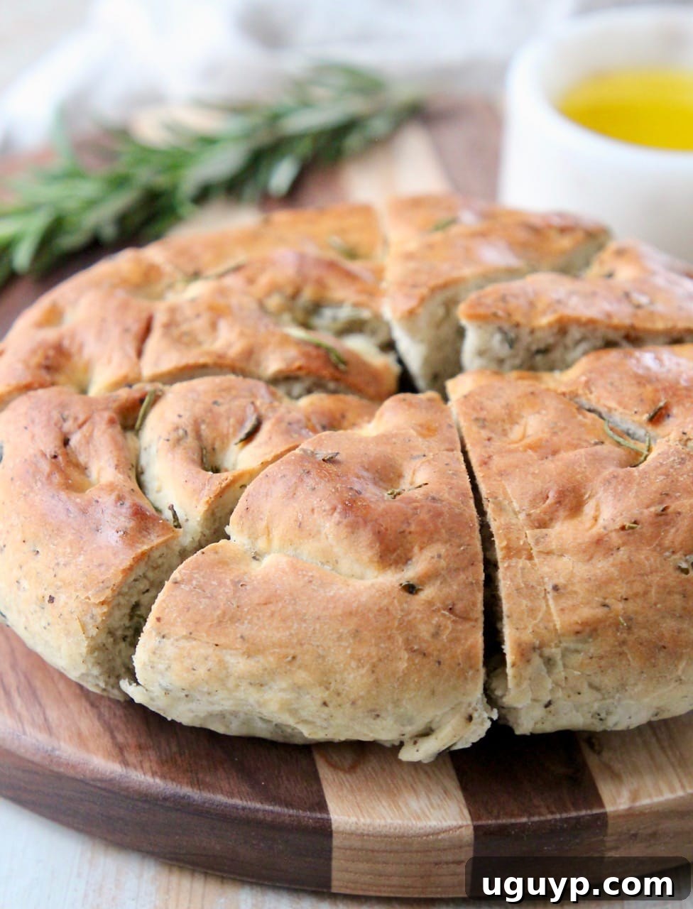 Round focaccia bread cut into diagonal slices on wood cutting board