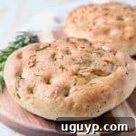 Focaccia Bread on wood cutting board with fresh rosemary sprigs