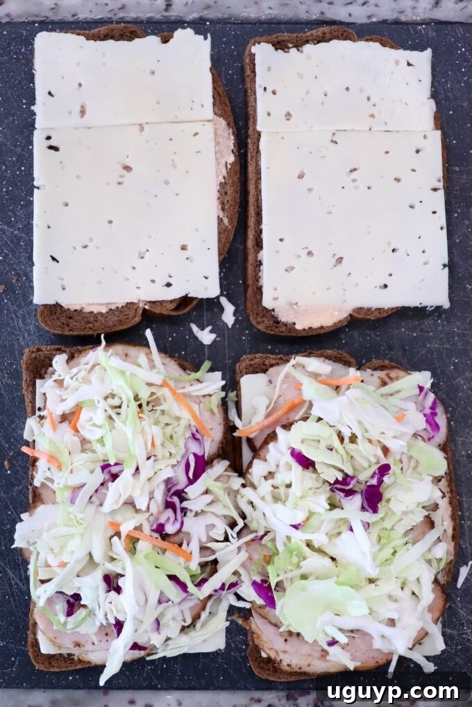 Open rye bread sandwiches: two with sliced cheese, two with coleslaw and meat, on a dark surface.