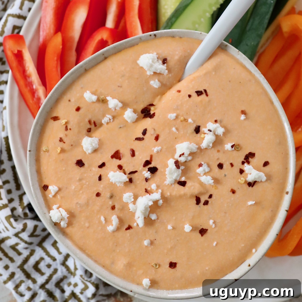roasted red pepper feta dip in bowl topped with feta cheese crumbles and red pepper flakes