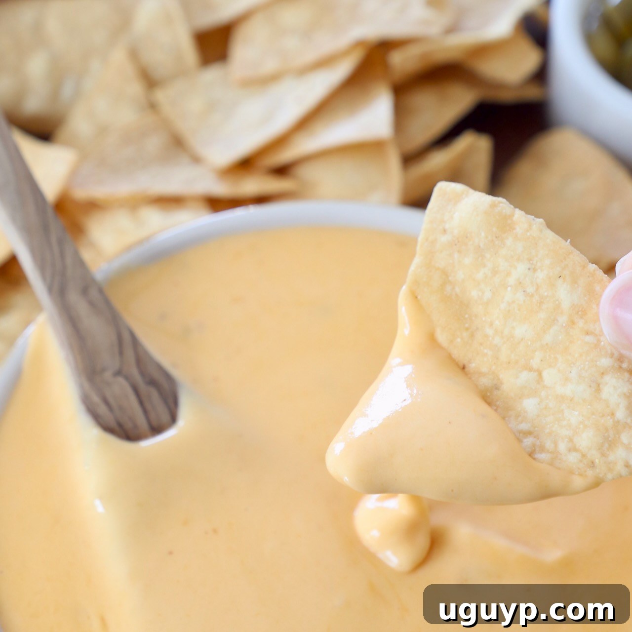 tortilla chip dipped into bowl of nacho cheese sauce