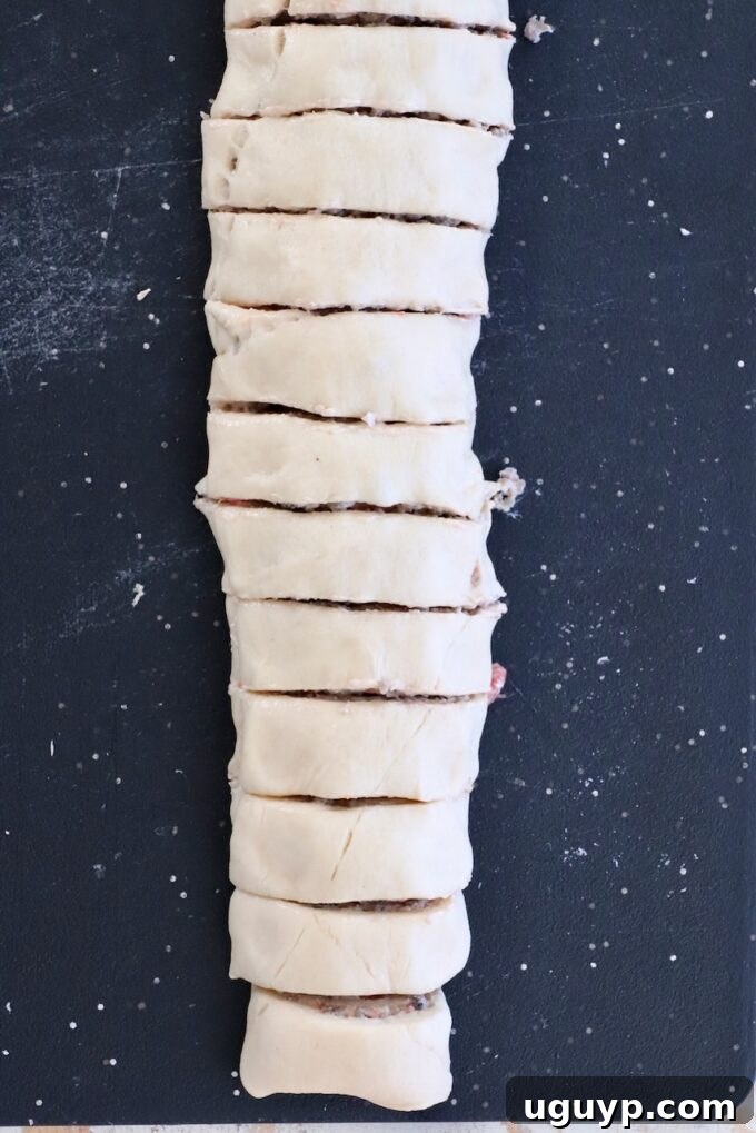 Dough rolled up with filling, sliced into even pieces, laid vertically on a black surface