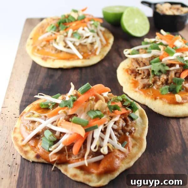 Beautifully plated Thai Peanut Pulled Pork Pizzas, garnished with lime wedges and fresh herbs.