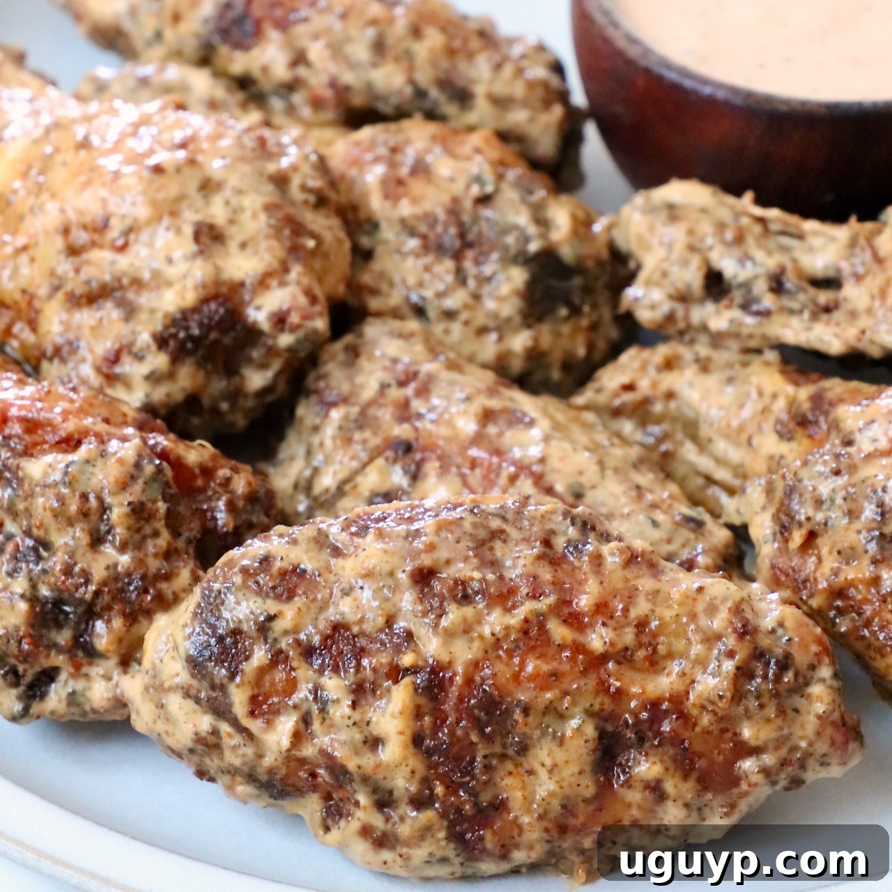 cooked chicken wings tossed in a creamy sauce on a plate