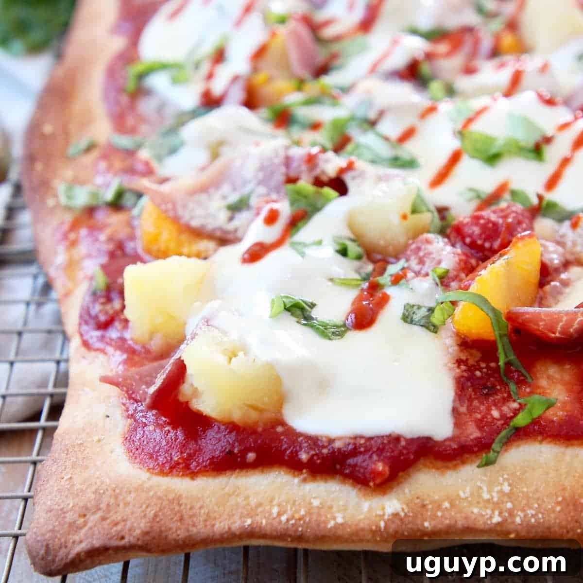 Hawaiian pizza on wire baking rack topped with pineapple, mandarin oranges and mozzarella cheese