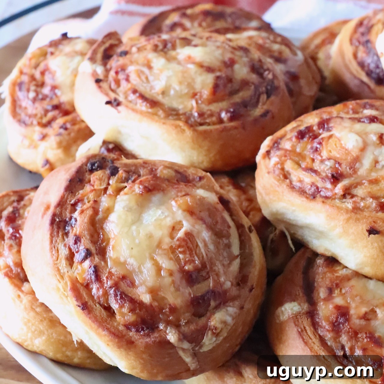 Close-up of golden-brown french onion rolls on a white plate. The swirled bread shows a crispy texture.