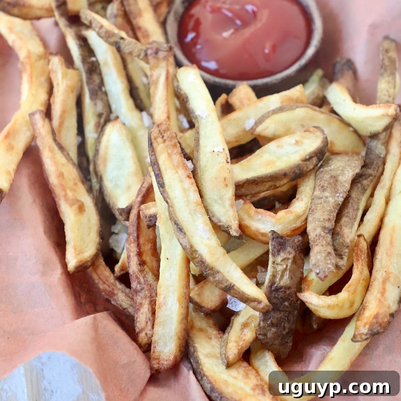 cooked french fries in basket with side bowl of ketchup