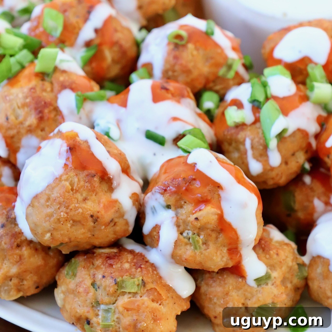buffalo chicken meatballs on plate, topped with a drizzle of buffalo sauce and blue cheese dressing