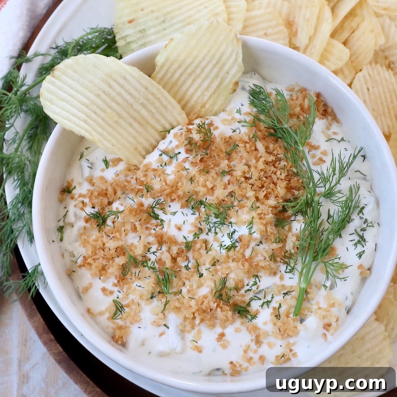 pickle dip in bowl topped with toasted breadcrumbs, with chips in the dip