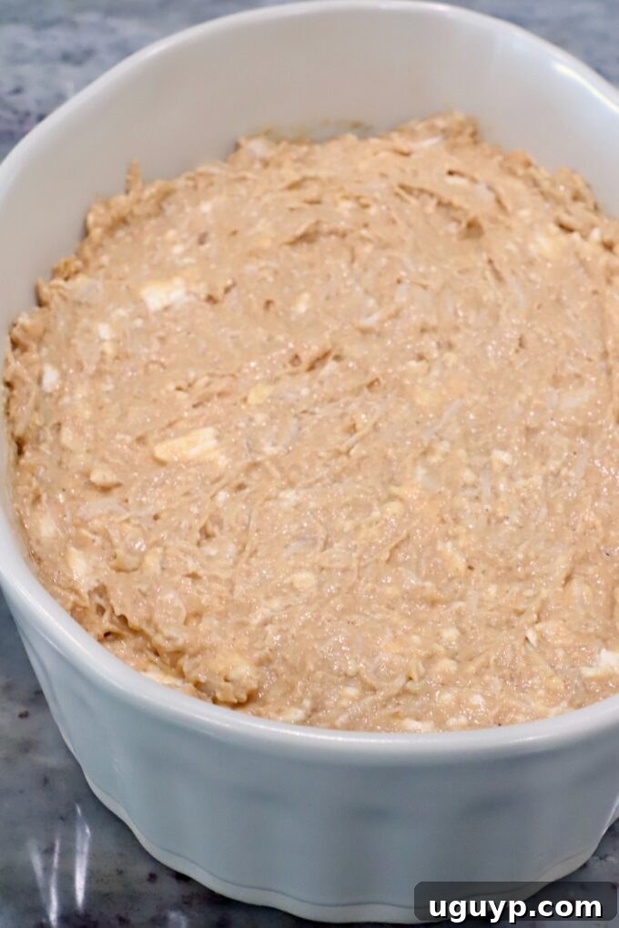 A white ceramic dish filled with unbaked creamy chicken dip