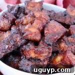 Close-up of glazed, caramelized pork belly bites in a white bowl, looking succulent and ready to eat.