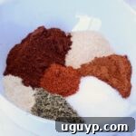 A white bowl containing vibrant heaps of spices, including red chili powder, paprika, oregano, and garlic powder, arranged in a colorful circle, representing the fresh homemade chorizo seasoning.