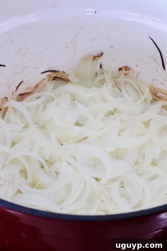 Richly caramelized onions glistening in a large Dutch oven after slow roasting in the oven.