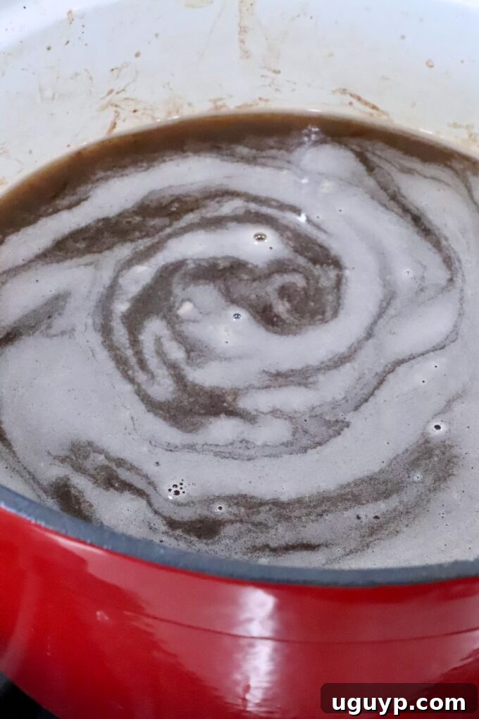 Rich beef stock and Worcestershire sauce simmering gently in a large pot, infused with the flavors of deglazed fond and roux.
