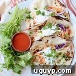 Tacos on plate with small wooden bowl of buffalo sauce on the side