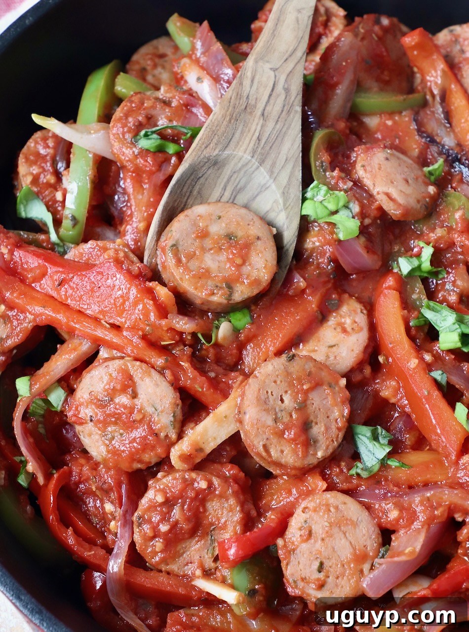 sliced sausage and peppers in skillet with wooden serving spoon, ready to be served
