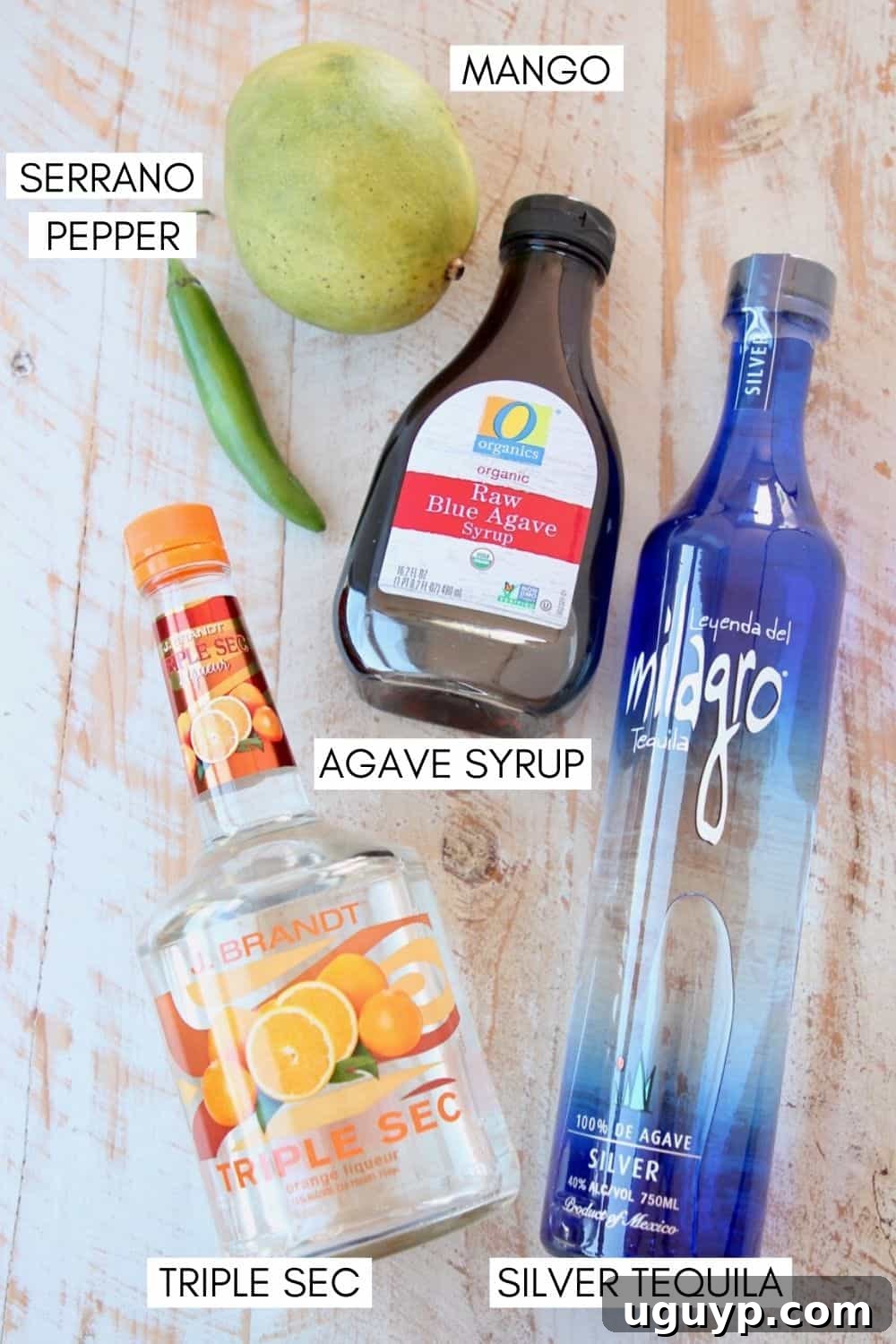 Fresh ingredients for making spicy mango margaritas, including diced mango, serrano peppers, silver tequila, triple sec, and agave nectar.