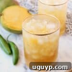 A close-up of a spicy mango margarita with fresh mango slices on the side.