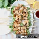 Overhead shot of chicken skewers on white plate