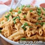 Close-up of creamy Buffalo Chicken Pasta in a bowl, topped with diced green onions.