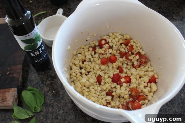 Grilled corn kernels, halved cherry tomatoes, and diced red onion in a large bowl, ready for dressing.