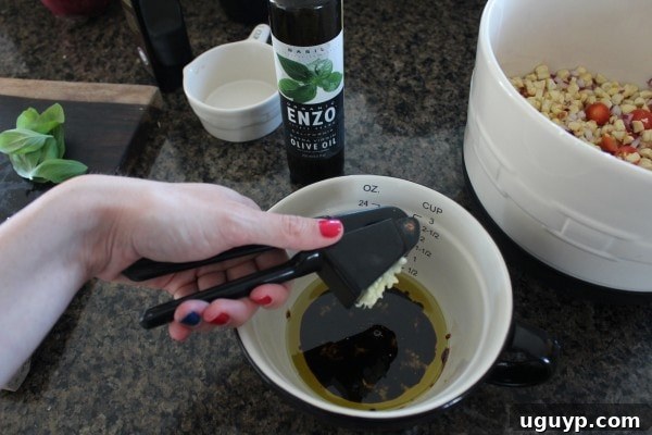 A small bowl with olive oil, balsamic vinegar, crushed garlic, and fresh basil being whisked together to form the salad dressing.
