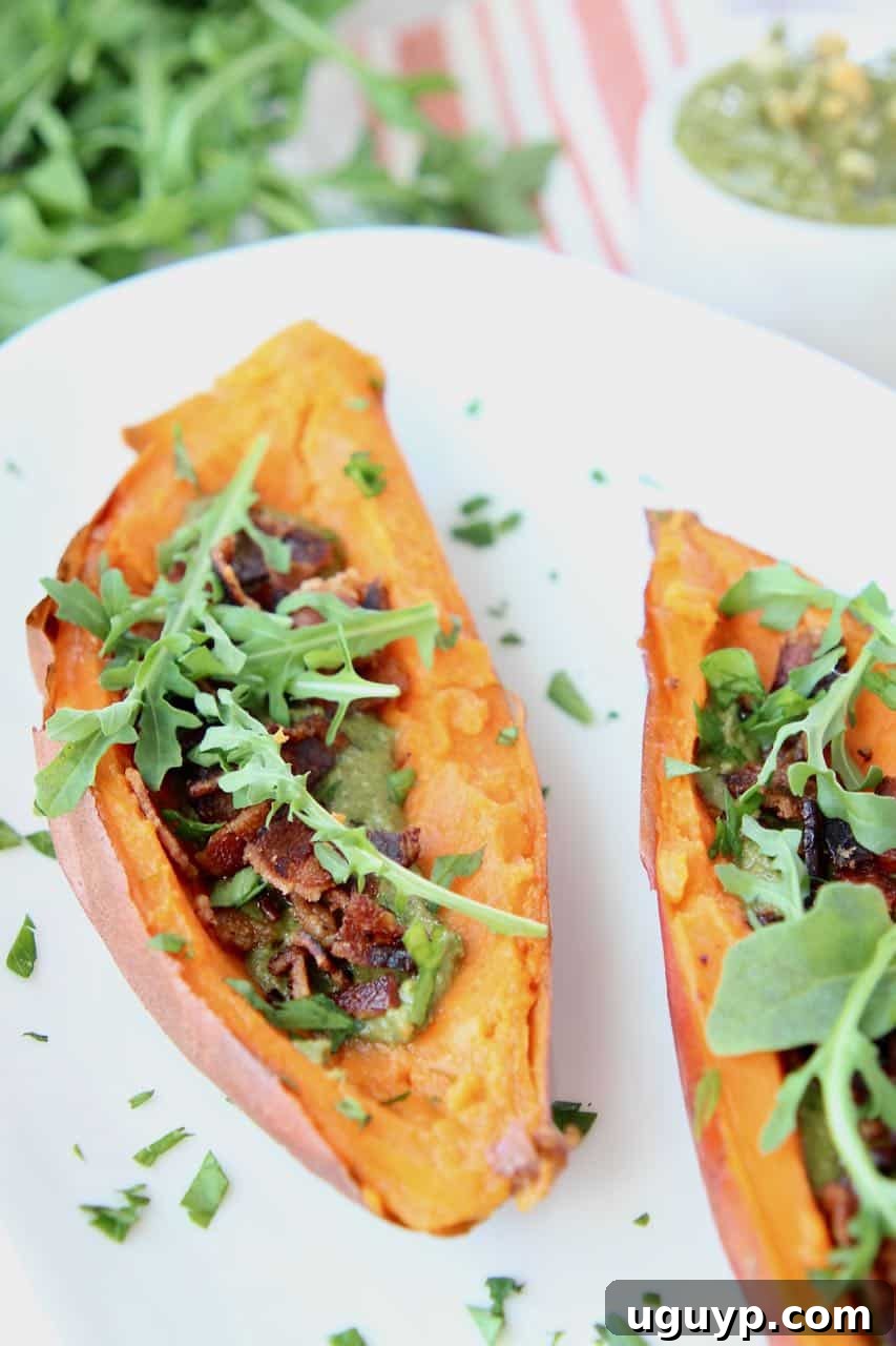 Loaded sweet potato skins with bacon and arugula on white plate