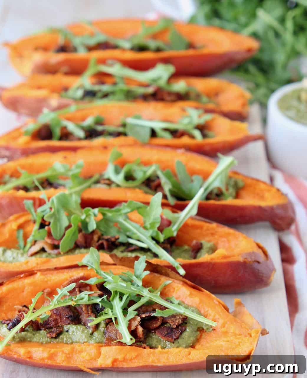 Sweet potato skins topped with arugula on wood cutting board