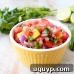 A small dish of vibrant, homemade Mango Salsa featuring diced mango, tomatoes, and other fresh ingredients.