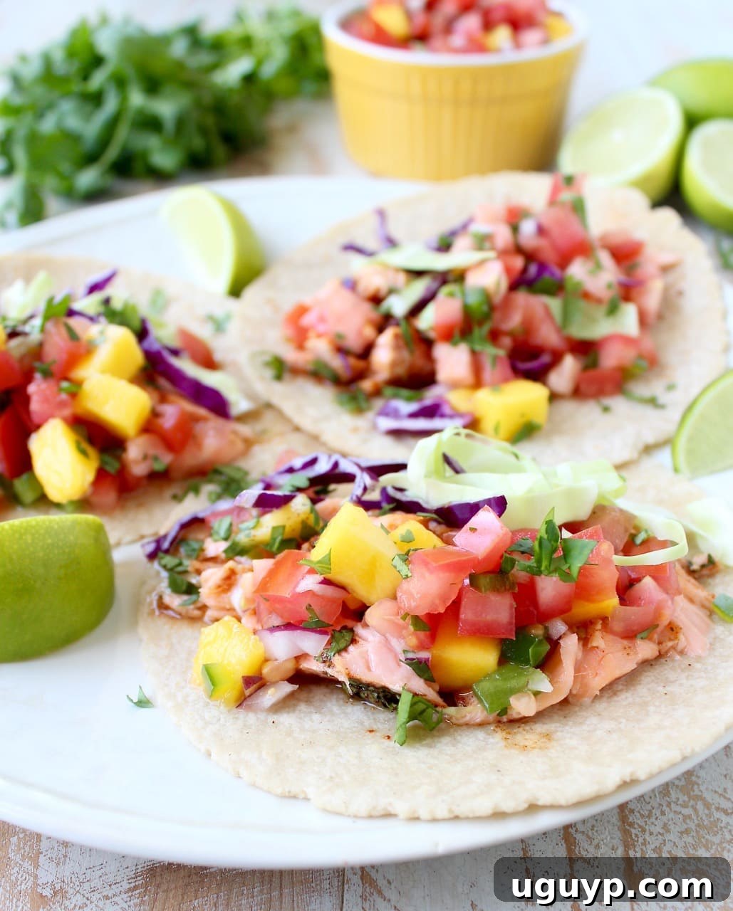 Delicious Chipotle Honey Glazed Salmon Tacos topped with fresh mango salsa and a side of lime wedges