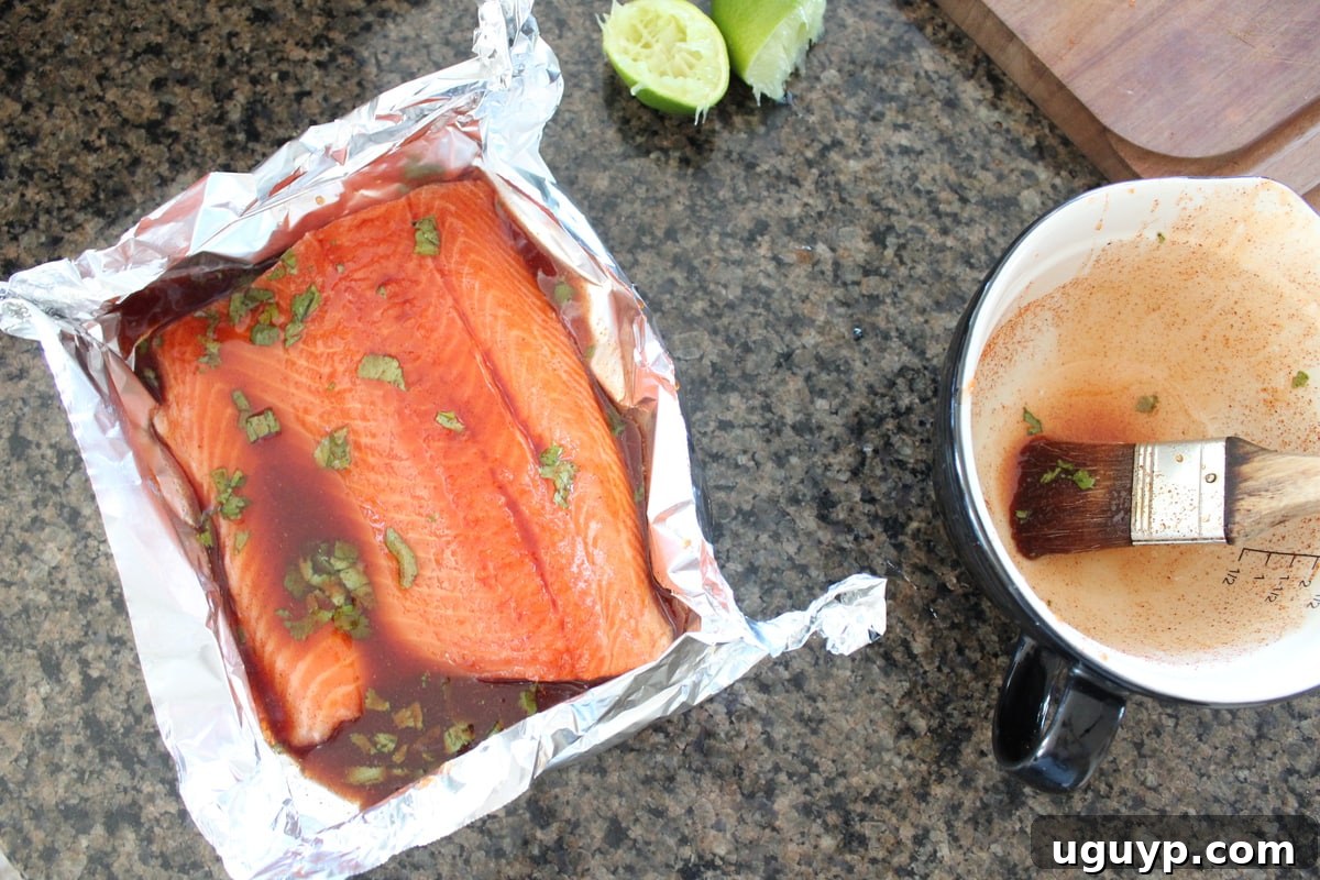 Raw salmon fillet covered in a rich chipotle honey glaze, prepared in an aluminum foil basket