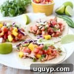 Chipotle honey glazed salmon is placed in warm corn tortillas & topped with fresh mango salsa in this mouth-watering recipe for healthy salmon tacos!