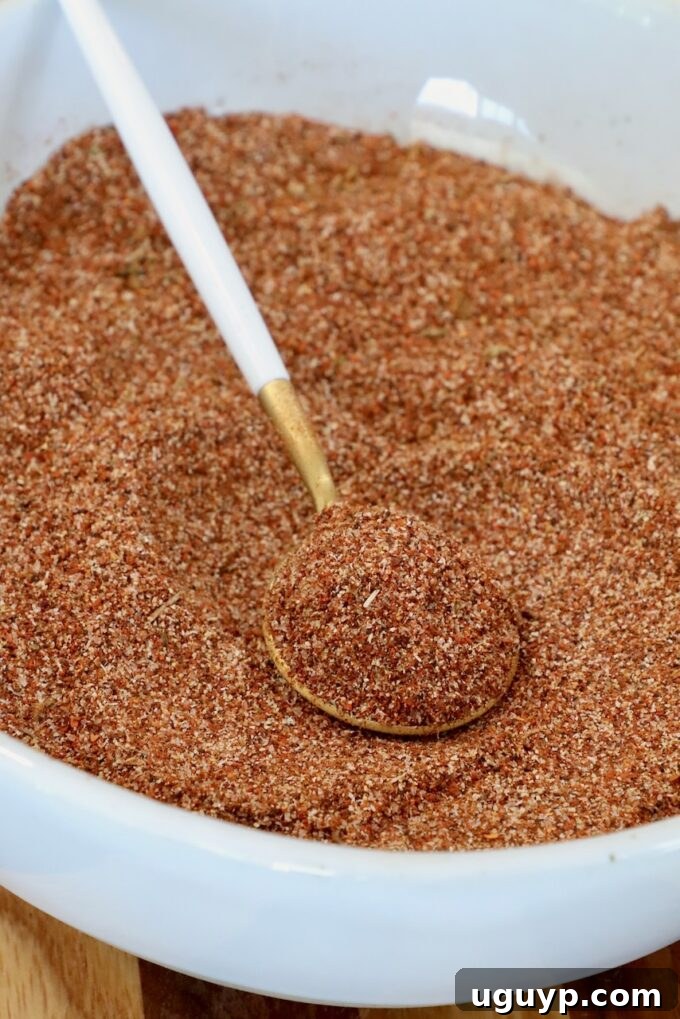 Al pastor seasoning mix in a bowl with a spoon, showing the vibrant color and rich texture of the freshly blended spices, ready to infuse flavor into any dish.