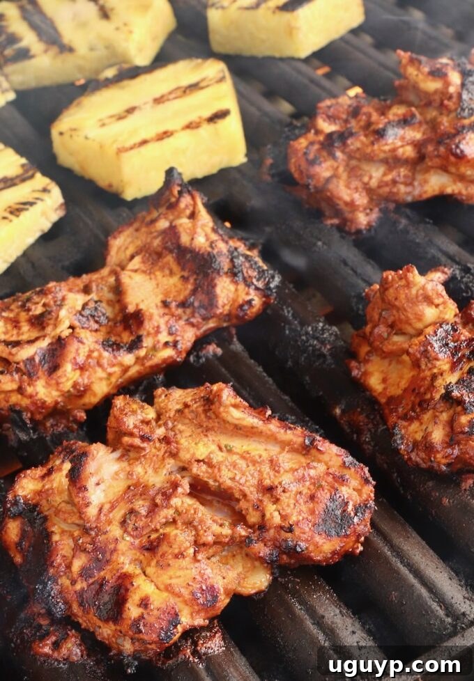 grilled marinated chicken thighs and pineapple slices on a grill