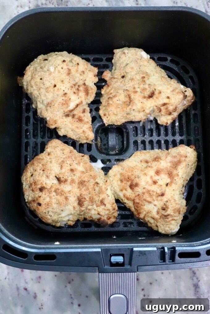 cooked pieces of chicken in an air fryer basket