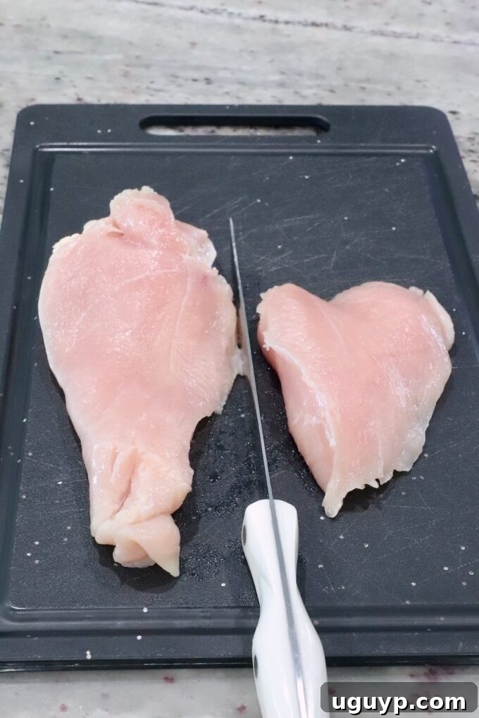 Chicken breast sliced in half on a cutting board, ready for seasoning.